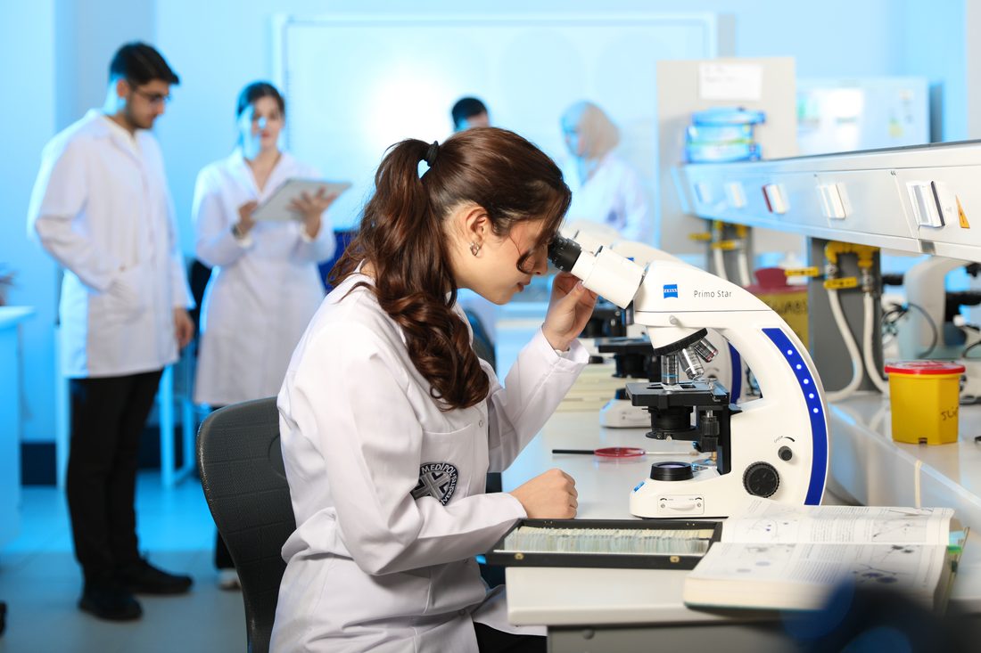 Laboratuvarda mikroskopla çalışan araştırmacı